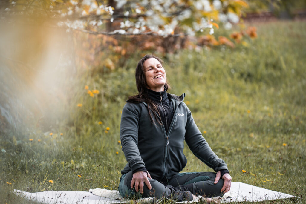 Jessica sittandes i yogaposition utomhus bland körsbärsblom