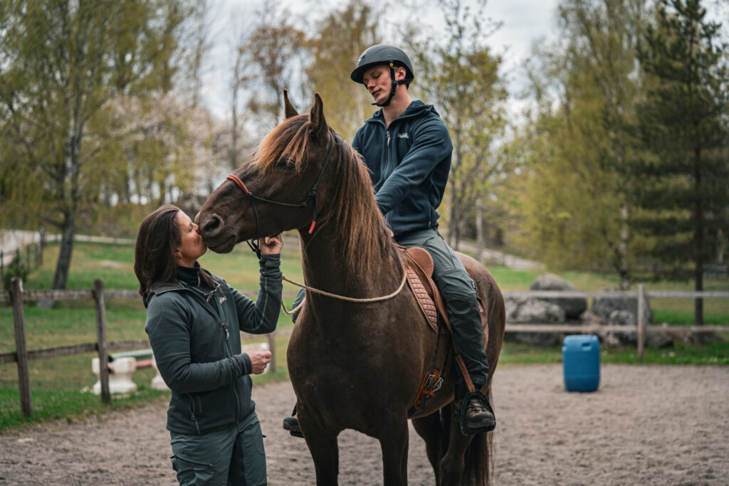 Jessica står med en häst. hennes son sitter på hästen.